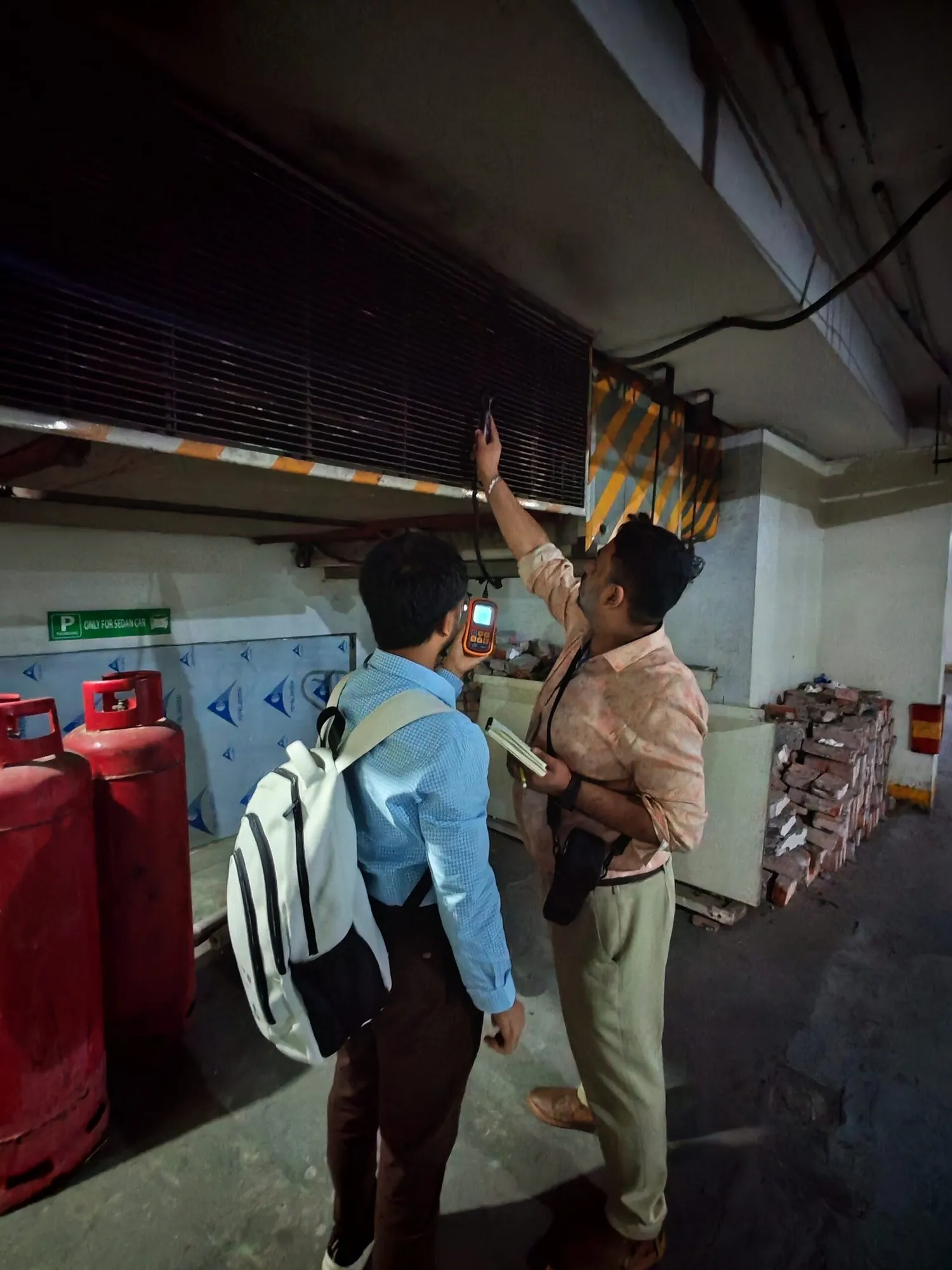 Two engineers inspecting an electrical room beside gas cylinders