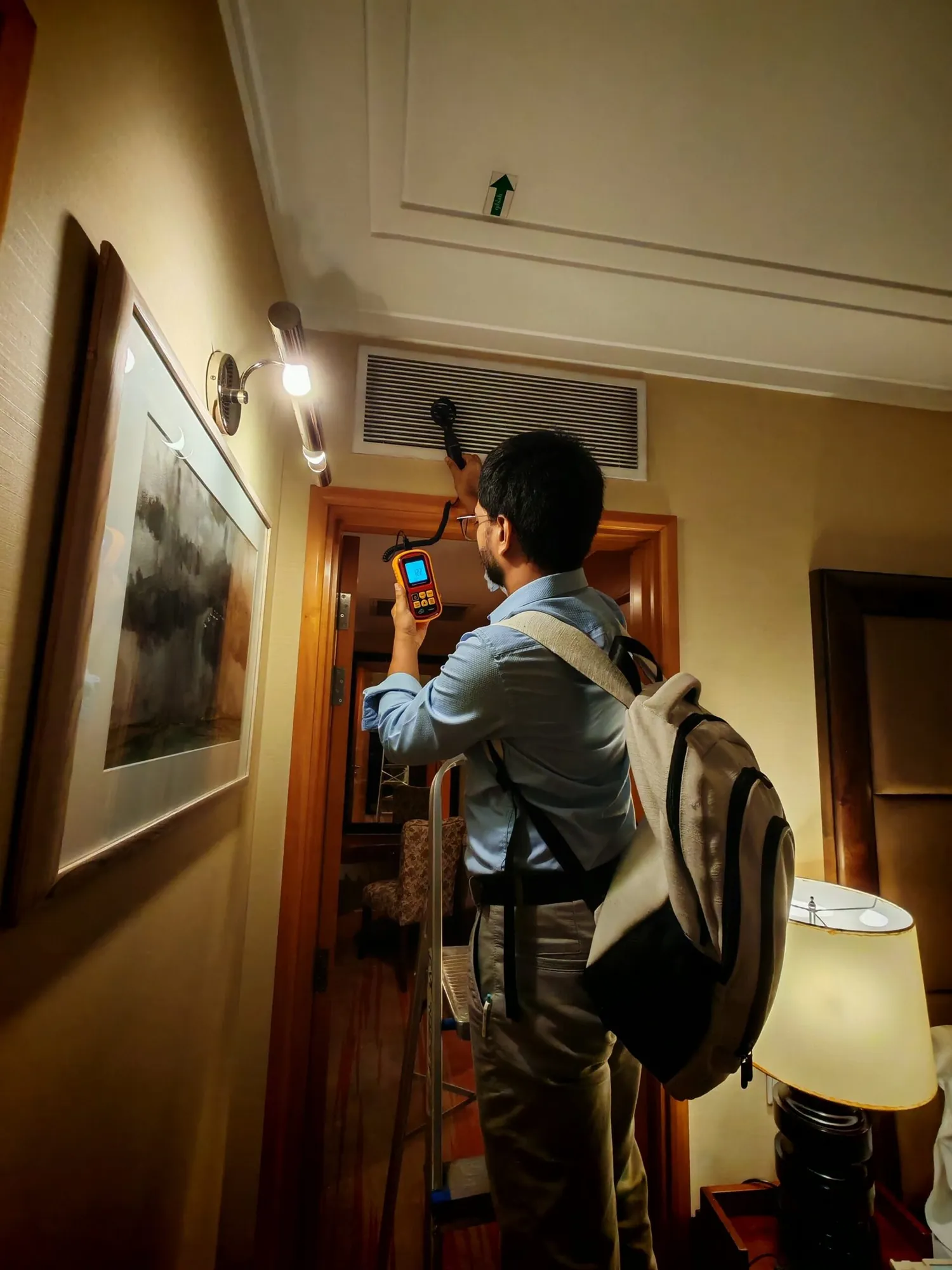 Engineer taking measurements beside a hotel service wall