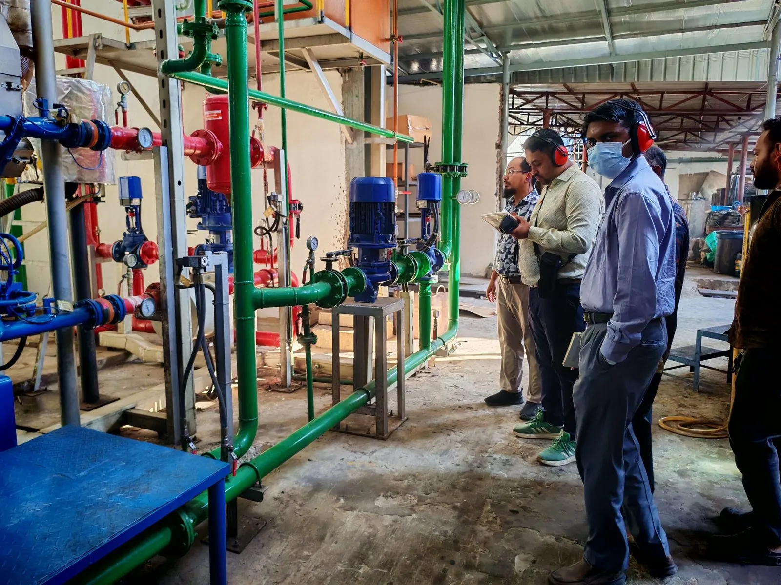 Engineers walking through a pump room with blue pumps and fire hydrants