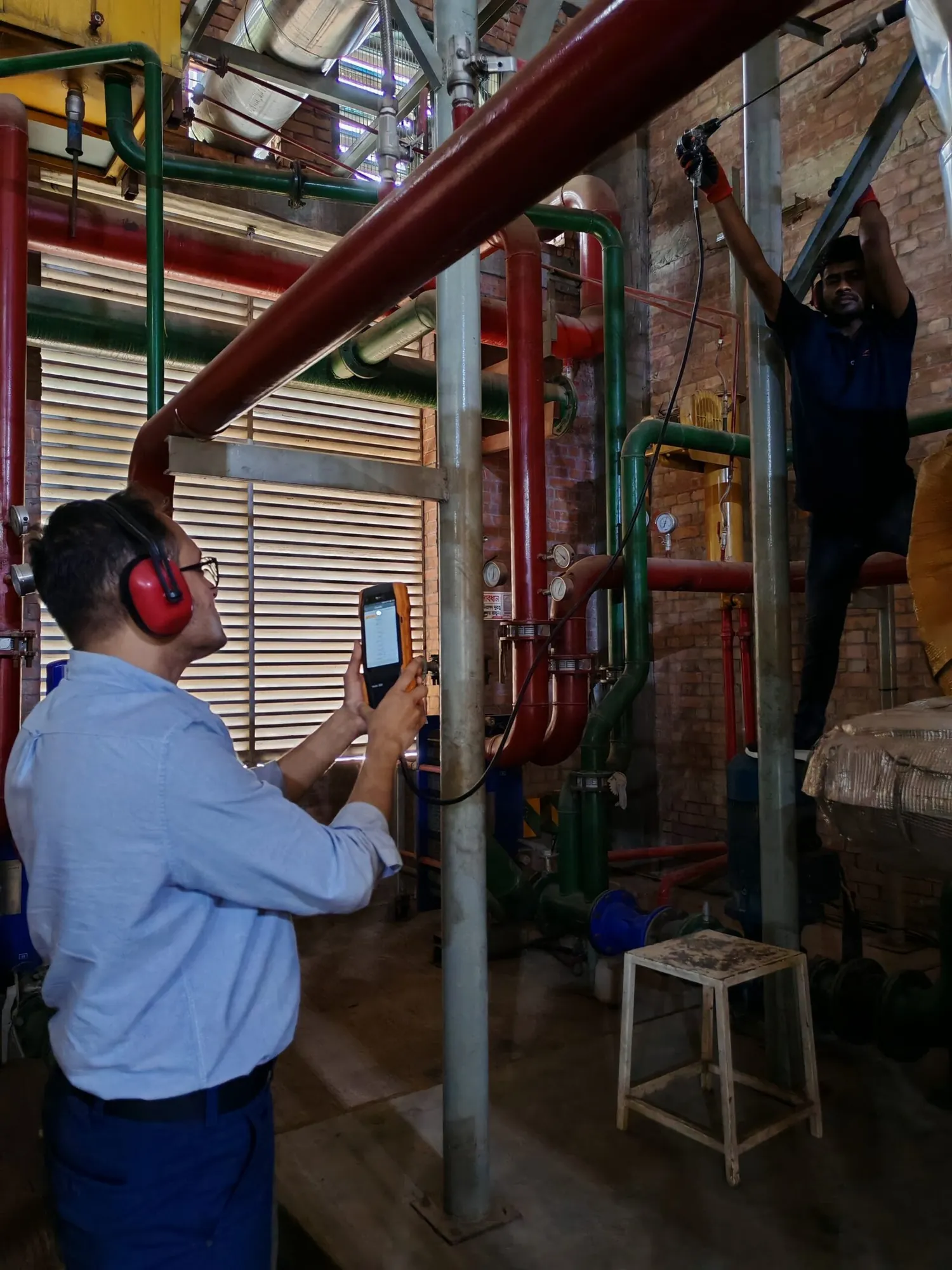 Engineer wearing ear defenders taking readings beside a pipe riser
