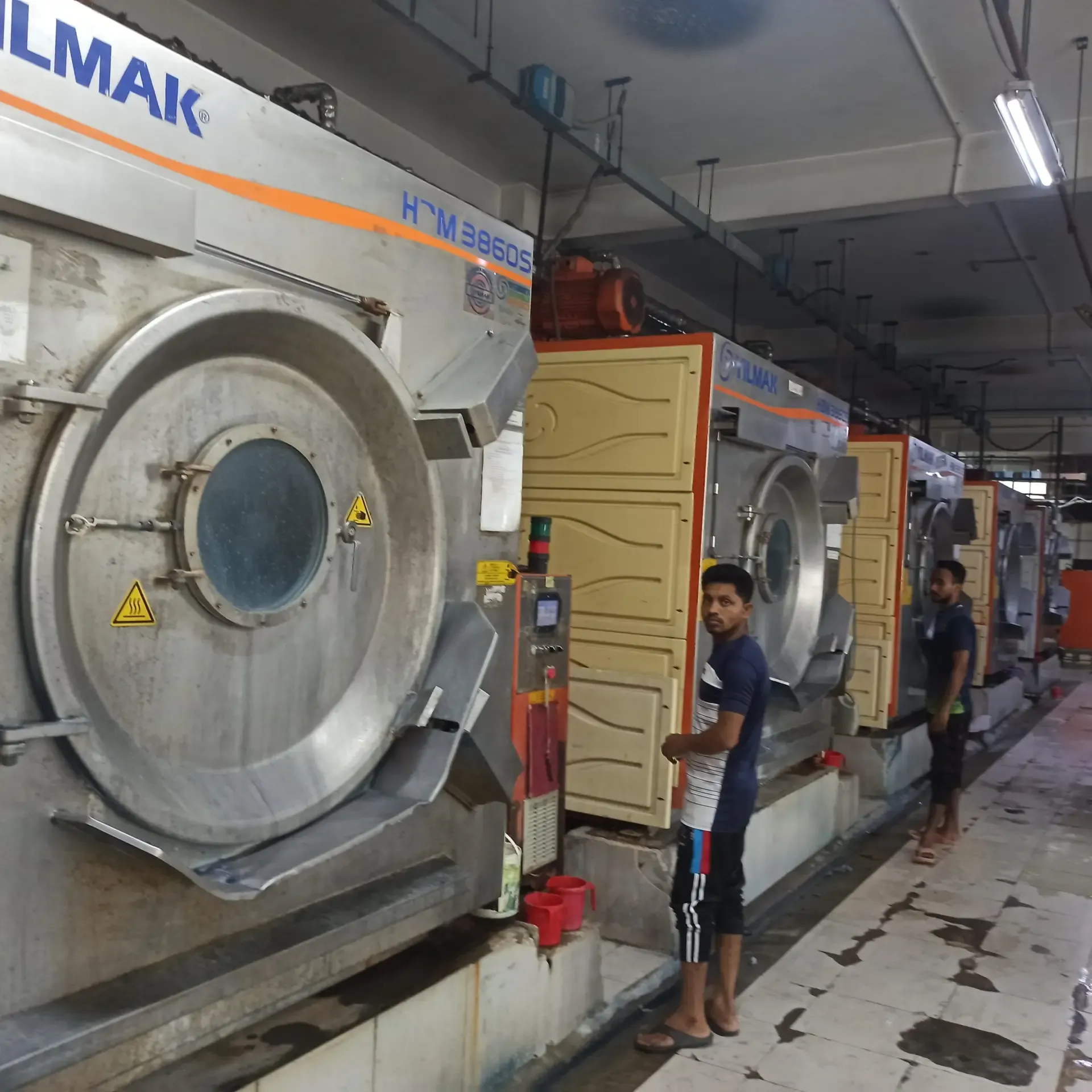Row of industrial washing machines in a garment washing plant